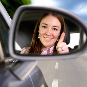 Photo of lady looking into rear vison mirror showing her reflection in it