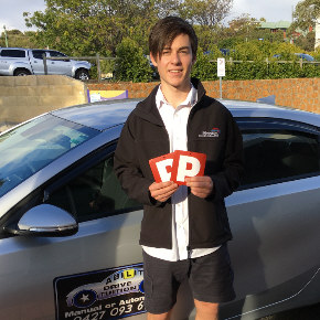 Male student standing next to driving school car showing P plates after passing driving test
