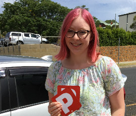 Red haired young female student standing by our driving school vehicle showing both P plates