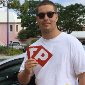 Male Student holding up P plates after passing driving test