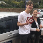 Male Student standing next to driving instructor, holding P plates after passing driving assessment